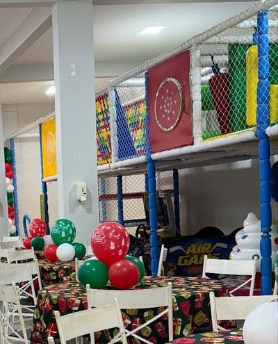 Brinquedão de dois andares com rede de proteção e colunas almofadadas, ao lado da máquina de air game