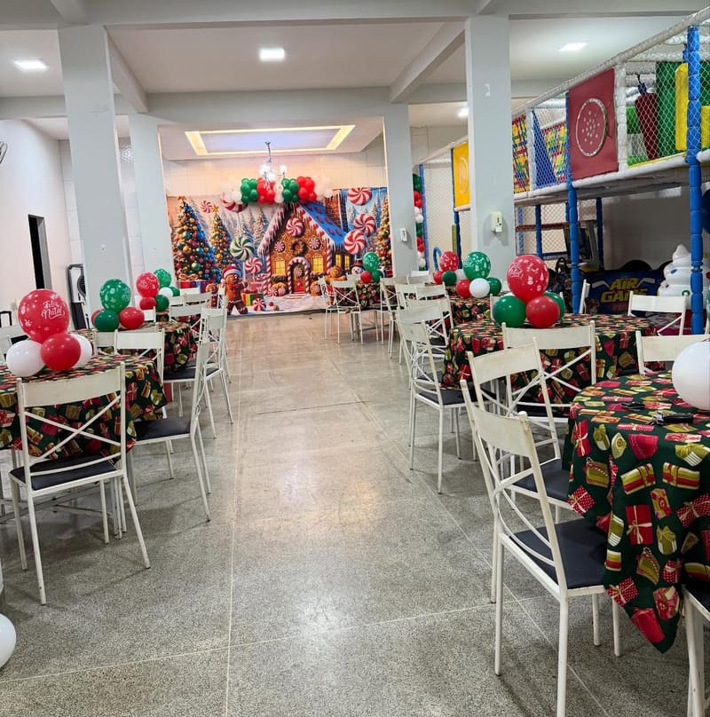 Salão da TOOP KIDS montado: mesas redondas com toalha, cadeiras brancas e painel decorado ao fundo