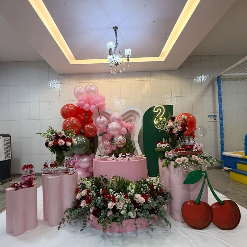 Decoração de cerejas com painel verde e rosa, cilindros, flores e o número dois